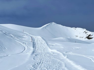 İsviçre Alpleri 'nin taze dağlık kar örtüsünde ve İsviçre' nin Grisonlar Kantonu, İsviçre 'nin turistik tatil beldesi Arosa' nın üzerinde harika kış yürüyüşü patikaları ve izler var.)