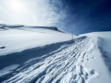 İsviçre Alpleri 'nin taze dağlık kar örtüsünde ve İsviçre' nin Grisonlar Kantonu, İsviçre 'nin turistik tatil beldesi Arosa' nın üzerinde harika kış yürüyüşü patikaları ve izler var.)