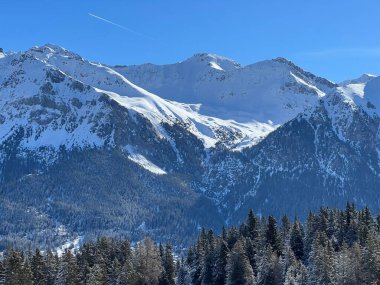 İsviçre 'nin Valbella ve İsviçre Alpleri' ndeki Lenzerheide tatil beldelerinin üzerindeki güzel güneş ışığı ve karlı alp zirveleri - Kanton Grisonlar Kantonu, İsviçre (Kanton Graubuenden, Schweiz)