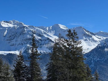 İsviçre 'nin Valbella ve İsviçre Alpleri' ndeki Lenzerheide tatil beldelerinin üzerindeki güzel güneş ışığı ve karlı alp zirveleri - Kanton Grisonlar Kantonu, İsviçre (Kanton Graubuenden, Schweiz)