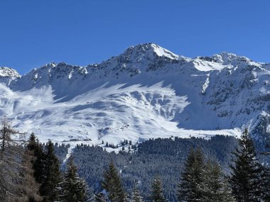 İsviçre 'nin Valbella ve İsviçre Alpleri' ndeki Lenzerheide tatil beldelerinin üzerindeki güzel güneş ışığı ve karlı alp zirveleri - Kanton Grisonlar Kantonu, İsviçre (Kanton Graubuenden, Schweiz)