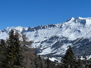 İsviçre 'nin Valbella ve İsviçre Alpleri' ndeki Lenzerheide tatil beldelerinin üzerindeki güzel güneş ışığı ve karlı alp zirveleri - Kanton Grisonlar Kantonu, İsviçre (Kanton Graubuenden, Schweiz)