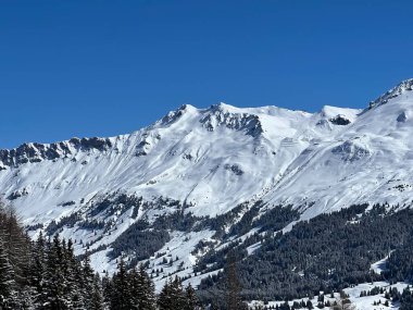 İsviçre 'nin Valbella ve İsviçre Alpleri' ndeki Lenzerheide tatil beldelerinin üzerindeki güzel güneş ışığı ve karlı alp zirveleri - Kanton Grisonlar Kantonu, İsviçre (Kanton Graubuenden, Schweiz)
