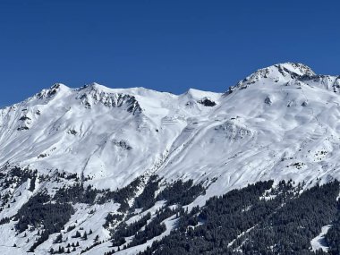İsviçre 'nin Valbella ve İsviçre Alpleri' ndeki Lenzerheide tatil beldelerinin üzerindeki güzel güneş ışığı ve karlı alp zirveleri - Kanton Grisonlar Kantonu, İsviçre (Kanton Graubuenden, Schweiz)