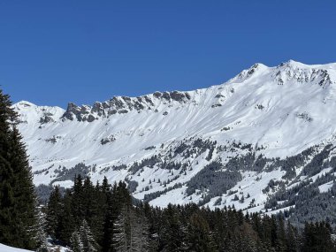 İsviçre 'nin Valbella ve İsviçre Alpleri' ndeki Lenzerheide tatil beldelerinin üzerindeki güzel güneş ışığı ve karlı alp zirveleri - Kanton Grisonlar Kantonu, İsviçre (Kanton Graubuenden, Schweiz)