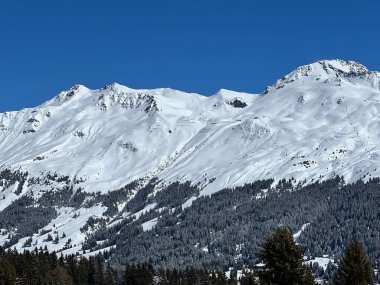 İsviçre 'nin Valbella ve İsviçre Alpleri' ndeki Lenzerheide tatil beldelerinin üzerindeki güzel güneş ışığı ve karlı alp zirveleri - Kanton Grisonlar Kantonu, İsviçre (Kanton Graubuenden, Schweiz)