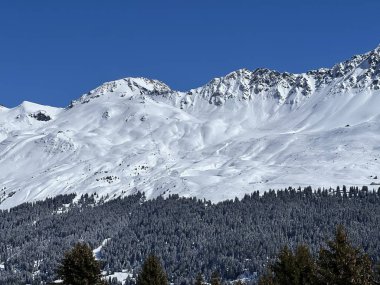 İsviçre 'nin Valbella ve İsviçre Alpleri' ndeki Lenzerheide tatil beldelerinin üzerindeki güzel güneş ışığı ve karlı alp zirveleri - Kanton Grisonlar Kantonu, İsviçre (Kanton Graubuenden, Schweiz)