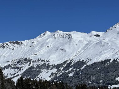 İsviçre 'nin Valbella ve İsviçre Alpleri' ndeki Lenzerheide tatil beldelerinin üzerindeki güzel güneş ışığı ve karlı alp zirveleri - Kanton Grisonlar Kantonu, İsviçre (Kanton Graubuenden, Schweiz)
