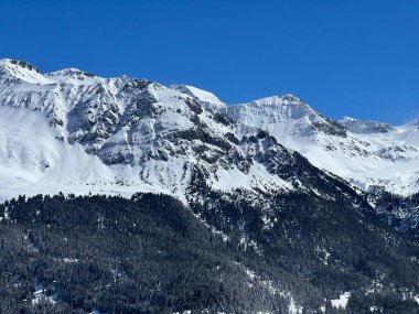 İsviçre 'nin Valbella ve İsviçre Alpleri' ndeki Lenzerheide tatil beldelerinin üzerindeki güzel güneş ışığı ve karlı alp zirveleri - Kanton Grisonlar Kantonu, İsviçre (Kanton Graubuenden, Schweiz)