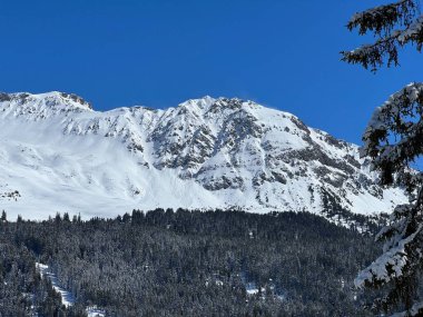 İsviçre 'nin Valbella ve İsviçre Alpleri' ndeki Lenzerheide tatil beldelerinin üzerindeki güzel güneş ışığı ve karlı alp zirveleri - Kanton Grisonlar Kantonu, İsviçre (Kanton Graubuenden, Schweiz)