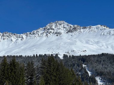 İsviçre 'nin Valbella ve İsviçre Alpleri' ndeki Lenzerheide tatil beldelerinin üzerindeki güzel güneş ışığı ve karlı alp zirveleri - Kanton Grisonlar Kantonu, İsviçre (Kanton Graubuenden, Schweiz)
