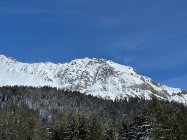 İsviçre 'nin Valbella ve İsviçre Alpleri' ndeki Lenzerheide tatil beldelerinin üzerindeki güzel güneş ışığı ve karlı alp zirveleri - Kanton Grisonlar Kantonu, İsviçre (Kanton Graubuenden, Schweiz)