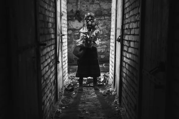 stock image Ukrainian woman in a gas mask, a pot with a plant. Dressed in a traditional folk costume. They hide in the basement bomb shelters from chemical, radioactive attacks, with poisonous gases, radiation