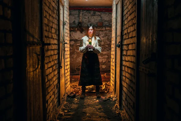 一个身着乌克兰传统服装的女孩站在黑暗的地下室里 手里拿着蜡烛 乌克兰悲剧的概念 炮击战争 — 图库照片