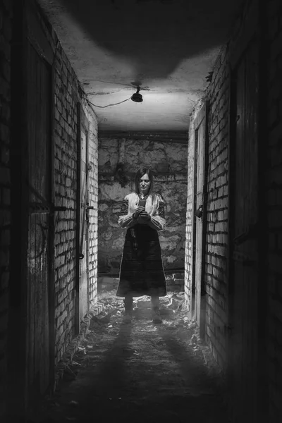 一个身着乌克兰传统服装的女孩站在黑暗的地下室里 手里拿着蜡烛 乌克兰的悲剧 炮轰战 垂直的照片 — 图库照片