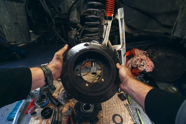 Car service from the first person mechanic. Male hands. Repair of the front wheel hub, replacement of Brake disc and pads, maintenance of a four-wheel drive SUV. Brake disc and pads.