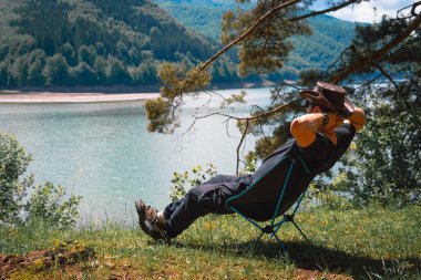 Sade ve kırsal bir manzara. Bir adam yürüyüş yaptıktan sonra dinleniyor ve dinleniyor katlanır bir sandalyeye oturuyor ve dağlardaki mesafeye bakıyor. Lake, Carpatians dağları Ukrayna