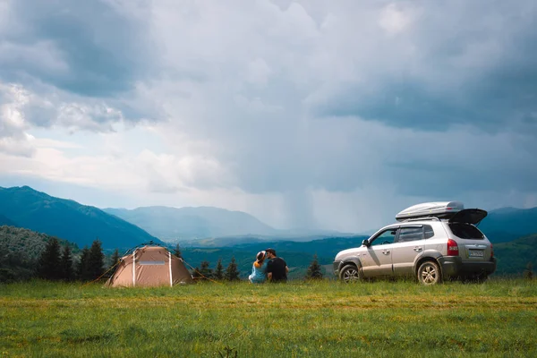 在山顶上 一对夫妇 一男一女 正在欣赏群山的美景 一个旅游帐篷和一辆四轮驱动汽车 车顶有车架 自由和旅行的概念 乌克兰 免版税图库图片