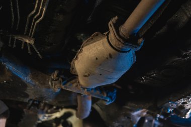 Gövdenin altındaki araç egzoz borusu, katalizör, rezonatör, egzoz sistemi. Eski parçalar tamir ve yenileme gerektirir. Araba servisi ve bakım. Standartlar ve teknik durum. seçici odak