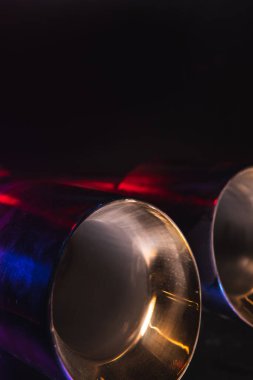 Krom, aracın egzoz sisteminin çift borusu. Araba ayarı için iyi bir ayrıştırıcı. Seçici odaklanma, karanlık arka plan. Uzayı kopyala Dikey fotoğraf.