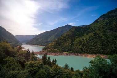 Mestia 'ya giden Emerland su deposu. Çam ormanı ve dağlarla çevrili İnguri Gölü 'nün güzel panoramik manzarası. Yaz, hava. Seyahat ve turizm