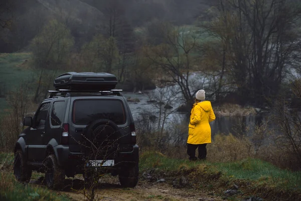 Bir Road Aracının Yanında Sarı Ceketli Bir Kadın Bulutlu Soğuk — Stok fotoğraf
