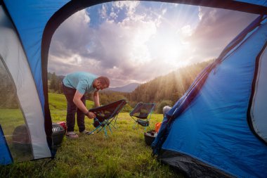 Turist çadırının içinden bak. Kamp gecesi düzenliyorum. Portatif sandalyeler, masa ve dağ manzaralı bir akşam yemeği. Yaz günü Ukrayna