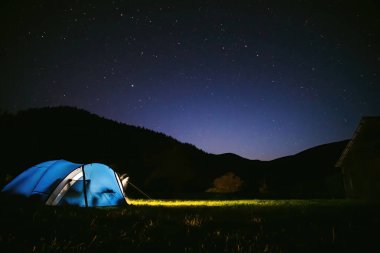 Turist çadırı ışıkla aydınlatılır. Yıldızlı gökyüzü. Turizm ve aktif eğlence. Bir gecede, Ukrayna 'nın Karpat dağlarında kamp kurduk. Boşluğu kopyala.