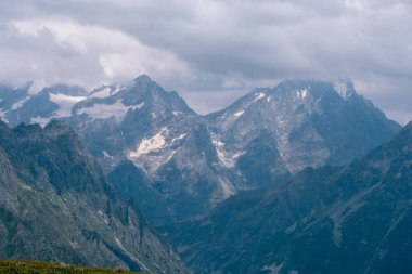 Dağın tepelerini, ılık yaz günlerini, gökyüzündeki bulutları, Ushba Dağı 'na ve Koruldi göllerine giden yolu. Tatil ve Georgia 'ya seyahat kavramı. Doğa, Mestia, Svaneti Dağları