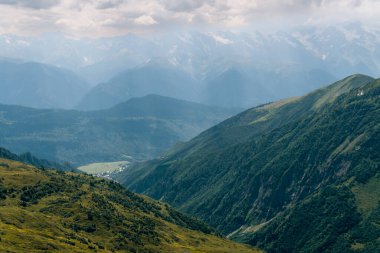 Dağın tepelerini, ılık yaz günlerini, gökyüzündeki bulutları, Ushba Dağı 'na ve Koruldi göllerine giden yolu. Tatil ve Georgia 'ya seyahat kavramı. Doğa, Mestia, Svaneti Dağları