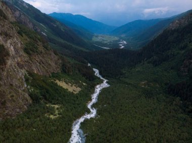 Kafkasya 'nın yüksek dağları arasında bir şelalenin hava manzarası, arka planda Ushba Dağı. Mazeri şehrinde bir vadi. Dolra Dağı 'nın fırtınalı akışı. Yaz tatili, Georgia 'da yürüyüş.