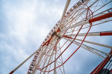 Big, tall white red Ferris wheel. Happy summer vacation feelings. Construction of metal pipes. Entertainment and recreation. Summer day. Batumi, Georgia. Copy space View from below