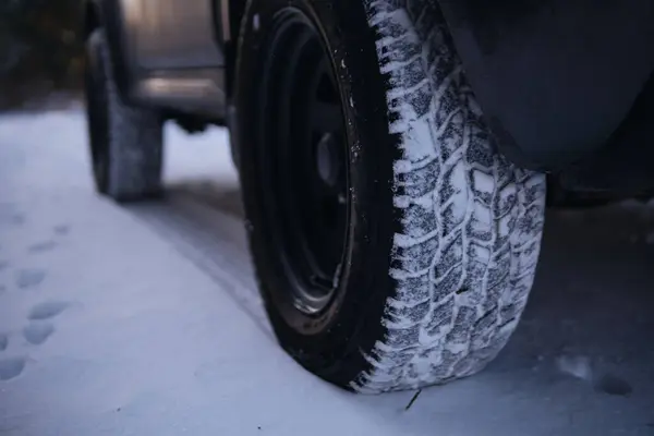 Closeup of car tires in winter on the road covered with snow. All terrain, season tire protector, for all weather conditions. M plus S, AT. Selective focus. Copy space