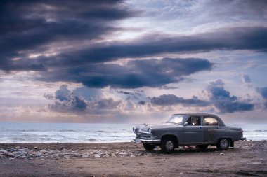Ureki, Georgia - August 13, 2021. GAZ M21 Volga. A retro vehicle stands on the beach. Stormy sea in the background, big waves, Heavy gray rain clouds. The concept of traveling by classic cars