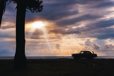 Ureki, Georgia - August 13, 2021. GAZ M21 Volga. A retro vehicle stands on the beach. Stormy sea in the background, big waves, Heavy gray rain clouds. The concept of traveling by classic cars