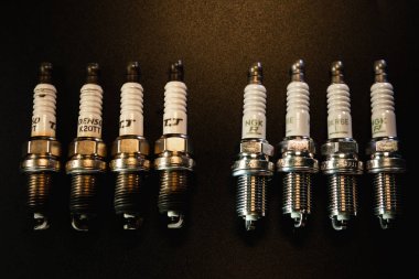 Khmelnytskyi, Ukrayna - 10 Şubat 2024: Yeni NGK ve eski Denso Japonya 'nın fişleri, benzin motorları. Siyah bir arka planda. Otomobil parçaları satış konsepti. Uzayı kopyala Üst alt görünüm