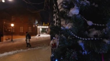 Karlı eski ahşap ev ve Noel ağacı. Cobblestone Caddesi. Yoldan geçenler karda yürürler ve soğuğa karşı kendilerini elbiselere sararlar..