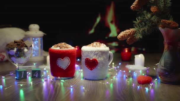 软视频明信片 圣瓦伦丁节热巧克力可可饮料加棉花糖 舒适的氛围与壁炉 格子花 花环和蜡烛 为杯子编织的盖子 有一颗心 — 图库视频影像