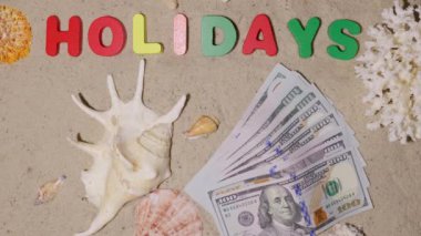 Tatil, tatil, hafta sonu için para. Pahalı bir sahil beldesinde hak edilmiş bir tatil. Kumsaldaki kumlarda dolar. Kumun üzerindeki yazı 