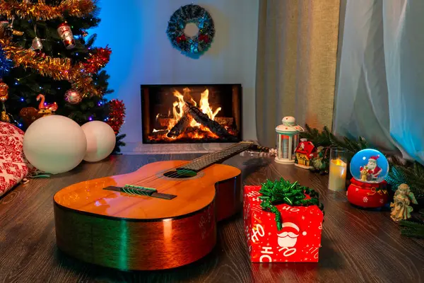 Şöminenin yanında Noel ağacı ve süslemeleri olan bir gitar. Konforlu Yeni Yıl ve Noel Sahnesi Müziği ve Festivalsel Tatil Dekoru.