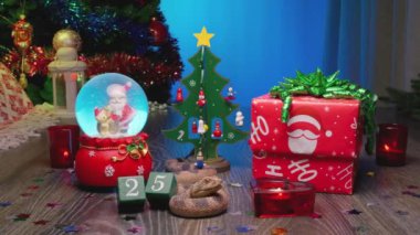 Yılan - Çin Ay takviminde 2025 Yılın Sembolü. Noel Hediyesi Kutusu, Noel Ağacı, Noel Baba ile Cam Kar Küresi, Kırmızı Mumlar ve 25 Numaralı Takvim.