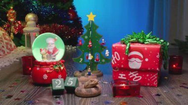 Yılan - Çin Ay takviminde 2025 Yılın Sembolü. Noel Hediyesi Kutusu, Noel Ağacı, Noel Baba ile Cam Kar Küresi, Kırmızı Mumlar ve 25 Numaralı Takvim.