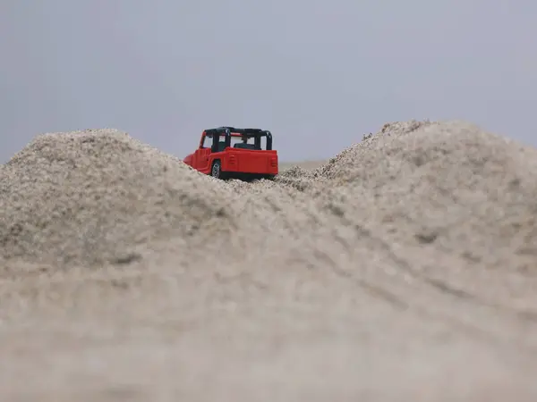 A small off-road vehicle glides across a sand dune or hill.