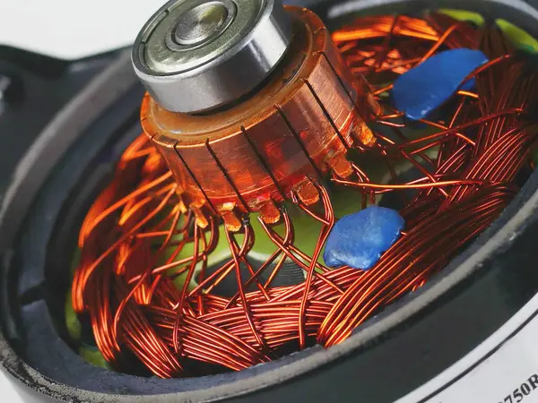 A close-up of the stator of an electric motor, featuring a coil of copper wires and a central bearing. The bright orange copper wires contrast with the metallic silver of the bearings.