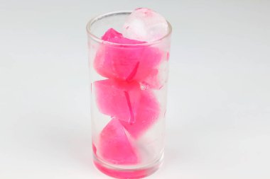 The image shows a clear glass filled with pink ice cubes.