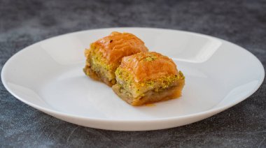 Beyaz tabakta fıstıklı baklava. Türk tarzı şam fıstıklı baklava sunumu ve hizmeti. Yatay görünüm.