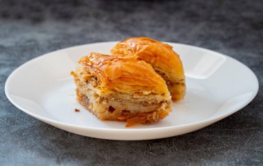 Beyaz tabakta fıstıklı baklava. Türk tarzı şam fıstıklı baklava sunumu ve hizmeti. Yatay görünüm.