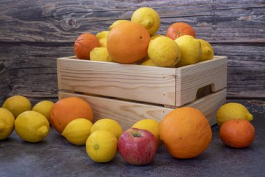 Freshly picked lemons, oranges, tangerines and apples in a Wooden Case.