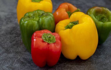 Sarı, kırmızı, yeşil dolmalık biberler gri arka planda .