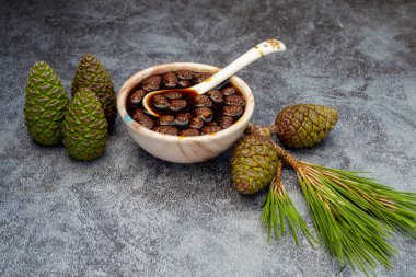 Genç kozalaklar gri mermer arka planda cam kasede sıkışıyor. Küçük kozalaklı lezzetli reçel.